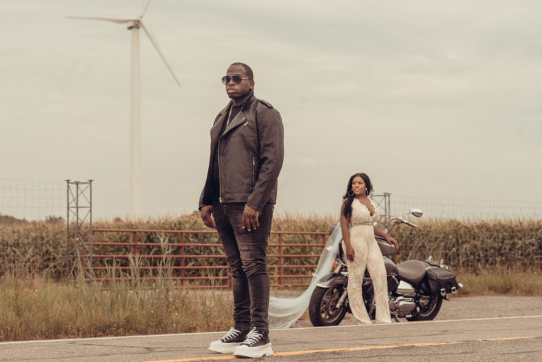 Groom poses in road and motorcycle